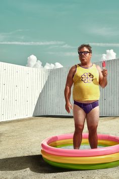 a man standing in front of an inflatable pool holding a comb and scissors