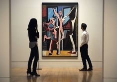 two people standing in front of a painting on display at an art museum, looking at it