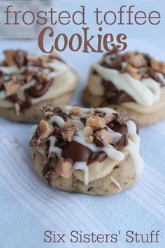 three cookies with white frosting and chopped walnuts are on a blue tablecloth