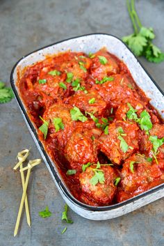 meatballs covered in marinara sauce and garnished with cilantro leaves