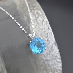 "Round Swiss Blue Topaz Solitaire Pendant Necklace - The stone is brilliantly faceted, has good clarity and is vivid 'Swiss Blue' in colour. The stone is set in a sturdy sterling silver bail with a sterling silver adjustable necklace chain.  * Stone: faceted Topaz gemstone, Swiss Blue, Stone size 12 X 12 mm  * December birthstone, December birthday pendant * Sterling silver pendant * Boxed, ready for gifting * Supplied with sterling silver diamond cut adjustable chain 18-20\"/45-50cm. We have th Blue Topaz Faceted Jewelry, Blue Topaz Jewelry With Brilliant Cut, Faceted Blue Topaz Jewelry, Blue Topaz Gemstone Necklace, Sapphire Jewelry With Diamond Cut Topaz, Classic Blue Topaz Round Stone Jewelry, Blue Topaz Round Stone Jewelry, Dazzling Blue Gemstones For Gift, Dazzling Blue Gemstones As Gift