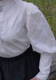 All cotton blouse with leg-o-mutton sleeves, lace ruffled collar and attached jabot, pintuck detailing on the front, back button closure. Hand or machine wash cold and tumble dry low or hang to dry. By Recollections and made in America. The model is wearing a skirt and it is priced separately. The following are approximate finished measurements and include room for ease of movement. Bust (in inches) XS37 S40 M44 L47 XL51 XXL56 3XL59 4XL63 Edwardian Blouse, Womens Blouses, Ruffled Collar, Cotton Blouse, Lace Ruffle, Pin Tucks, Custom Dresses, Hawks, Cotton Blouses