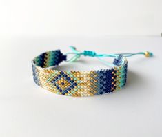 a blue and yellow beaded bracelet on a white surface with a string attached to it