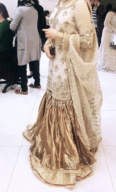 a woman in a white and gold outfit standing on the floor with other people around her