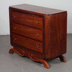 a wooden dresser sitting on top of a floor next to a white wall and grey floor