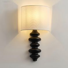 a wall mounted lamp with a white shade on it's face and bottom half