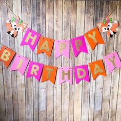 a pink and orange happy birthday banner hanging on a wooden wall