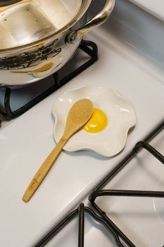 an egg in a frying pan on top of a stove with a wooden spoon