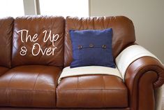 a brown leather couch with the words the up and over on it's pillow