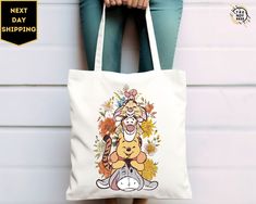 a woman holding a tote bag with an image of winnie the pooh on it