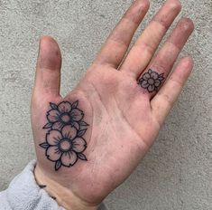 a person's hand with a flower tattoo on the middle of their left palm