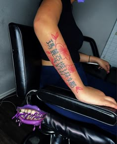 a woman with a tattoo on her arm sitting in a chair next to a purple object