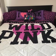 a bed with pink and black pillows on it