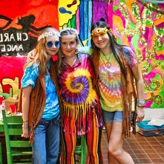 three girls standing next to each other in front of colorful wall