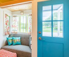 a living room with a couch, window and blue door in the center of it