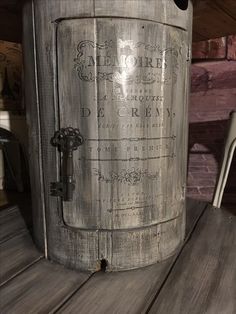 an old metal barrel sitting on top of a wooden table next to a white chair