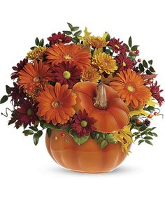 a pumpkin vase filled with orange and red flowers