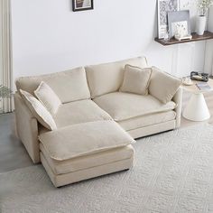 a living room with a large sectional couch and white rugs on the floor in front of it