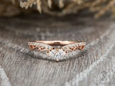 a rose gold wedding band with diamonds on it, sitting on top of a piece of fabric