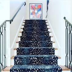 a stair case with blue and white designs on the carpet, next to a painting