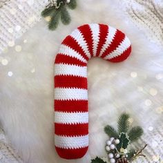 a red and white striped candy cane laying on top of a fur covered floor next to christmas decorations