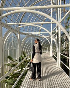 a woman standing on a walkway in a greenhouse