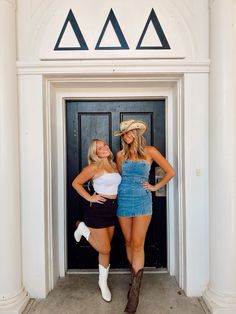 two beautiful women standing next to each other in front of a door wearing cowboy hats