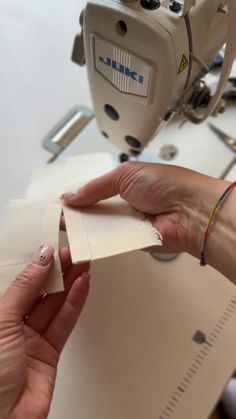 a woman is working on some paper with a sewing machine in the background