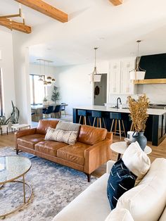 a living room filled with furniture next to a kitchen and dining room table in front of an open floor plan