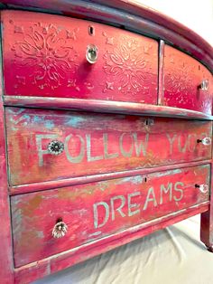 a red painted dresser with the words follow your dreams written on it's drawers