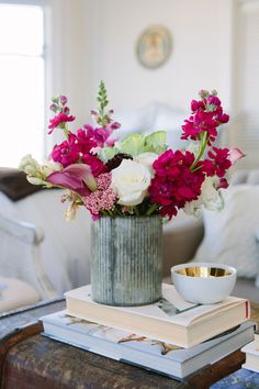 a vase filled with flowers sitting on top of a table next to a stack of books