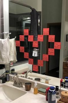 a bathroom sink with red sticky notes attached to the side of it and a mirror in the background