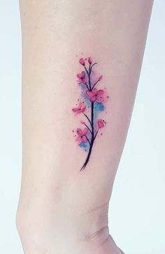 a small pink flower tattoo on the right side of the leg, with watercolors