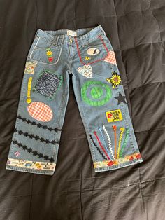 a child's jean pants with patches on it sitting on top of a bed