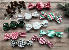 several bows are lined up next to pine cones and christmas decorations on a wooden table