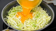 someone pouring orange juice into a bowl of shredded cabbage