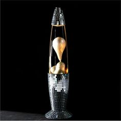 a silver and gold vase sitting on top of a black table next to a wall