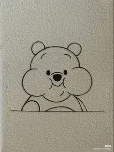 a drawing of a teddy bear on a white wall with black outline and the shape of a face