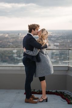 a man and woman kissing on top of a building