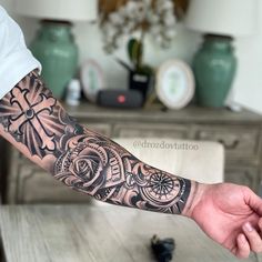 a man's arm with a clock and rose tattoo on the left forearm, in front of a table