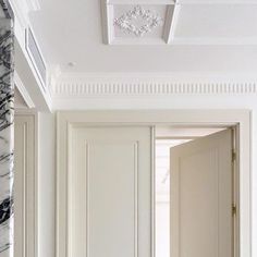 an open door leading to another room with white walls and trimmings on the ceiling