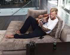 a man sitting on a couch with a guitar in his hand and holding a bottle