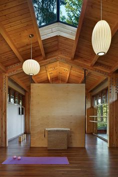 an empty room with wooden floors and two lamps hanging from the ceiling, along with yoga mats on the floor