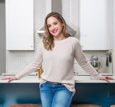 a woman sitting on top of a stool in a kitchen