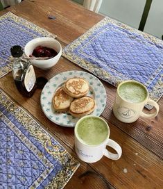 two cups of green tea and some pancakes on a table