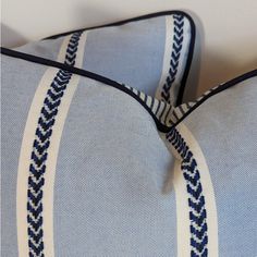 two blue and white pillows on top of each other, one has a braided edge