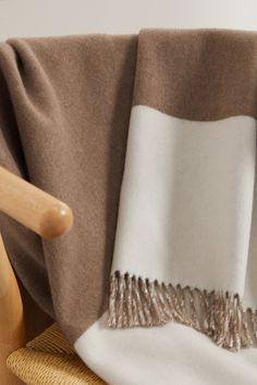 a brown and white blanket sitting on top of a wooden chair