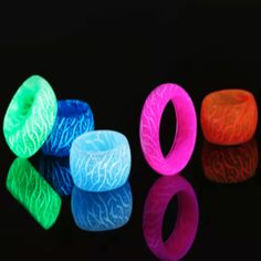 three different colored rings sitting next to each other on top of a black surface with reflections