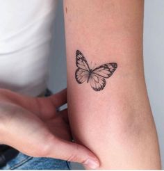 a small butterfly tattoo on the left inner arm and wrist is shown in black ink