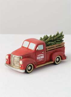 an old red truck with a christmas tree in the back and pine branches on top